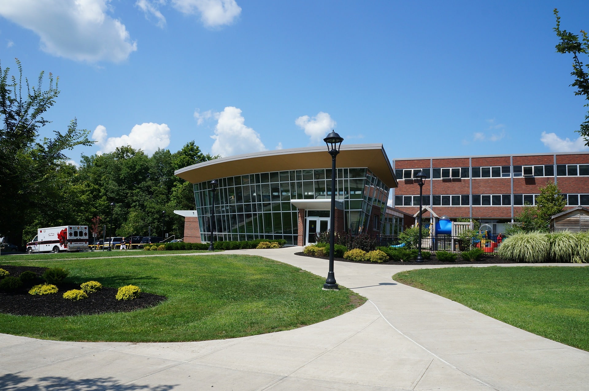 The outside of a modern school building with a large grassed and paved area.