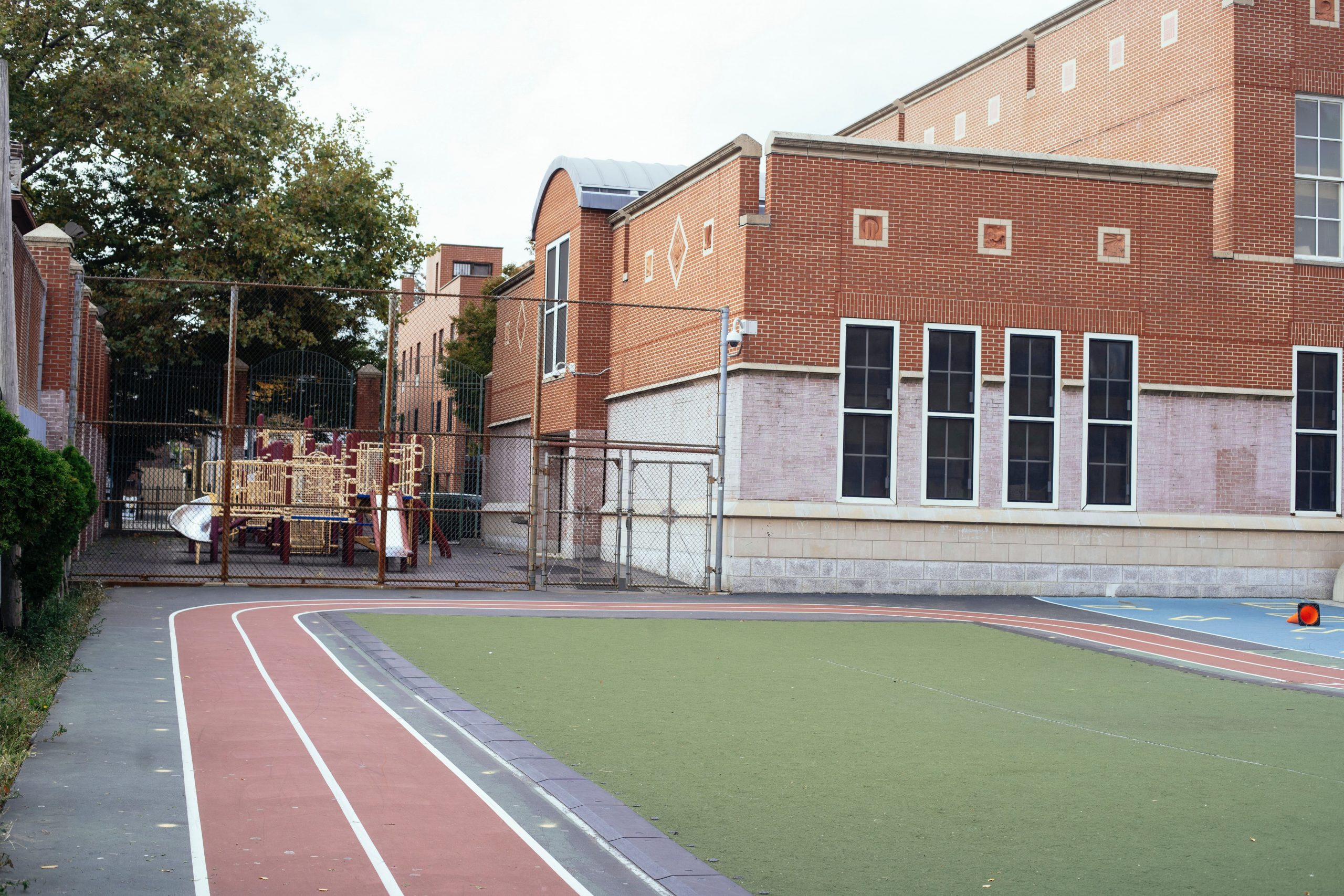 A running track in front of a bricked school building.